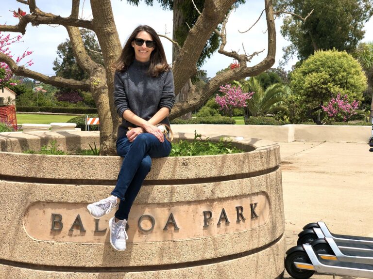 woman in front of the balboa park sign and tree in downtown san diego
