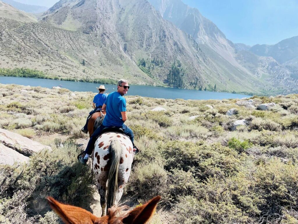 horseback riding with a view of convict lake in the summer