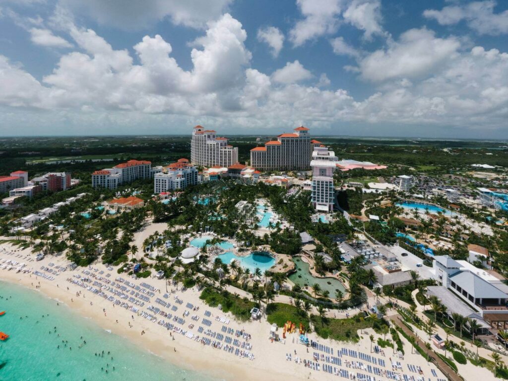 An overview photo of the entire Baha Mar Resort in Nassau, Bahamas showing lounge chairs on Cable Beach, several pools and highrise hotels