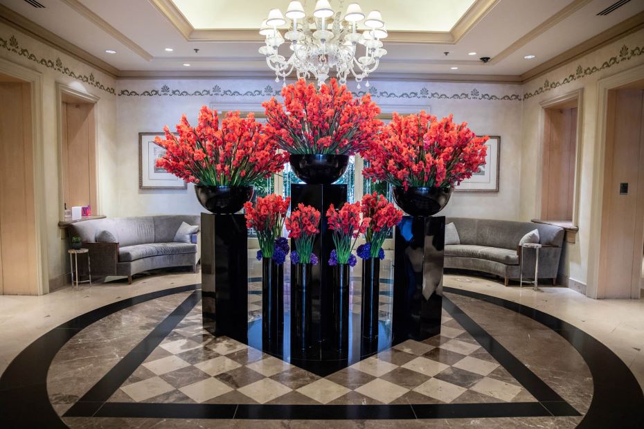 Flower installation of tall black pillars with black pots and red flowers at Four Seasons Los Angeles, designed by Jeff Leatham