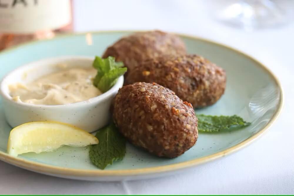 Fête Bistro by Slay's falafel balls on a plate with dipping sauce in Manhattan Beach