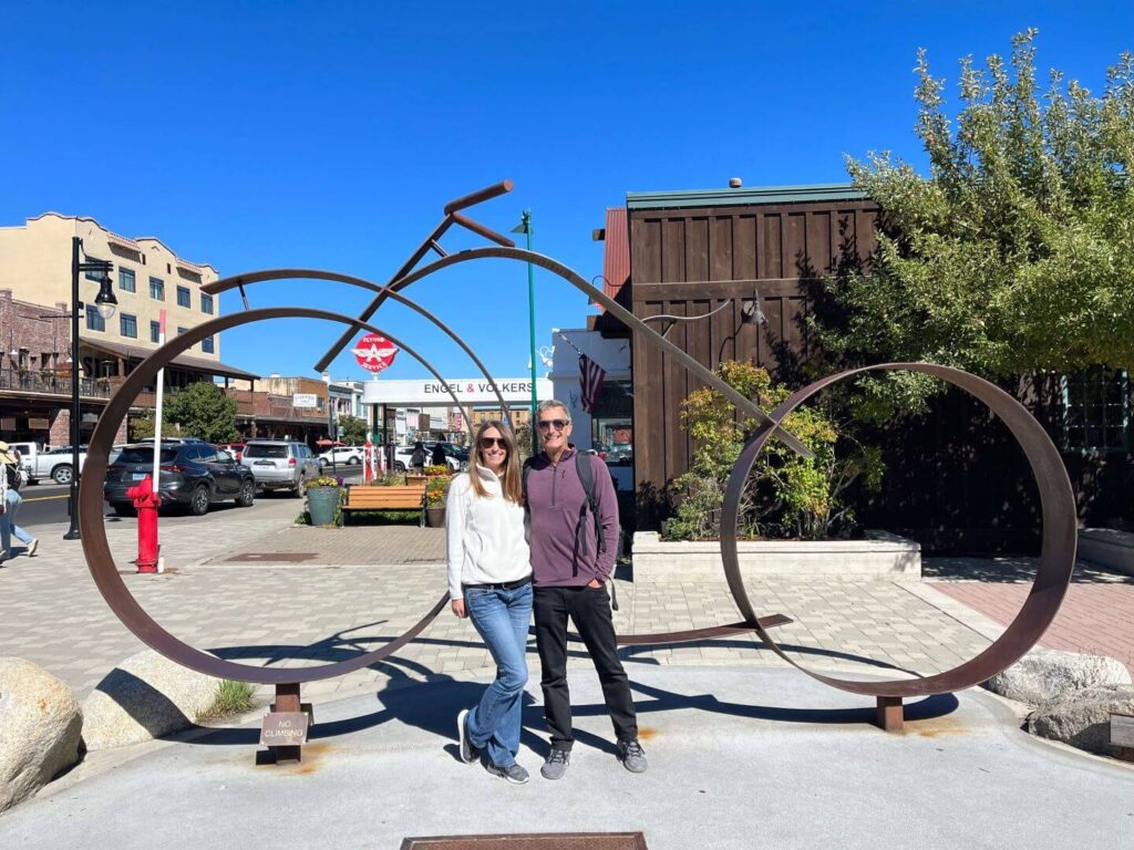 Couple stanidng in front of an extra large metal bike sculture in downtown Truckee