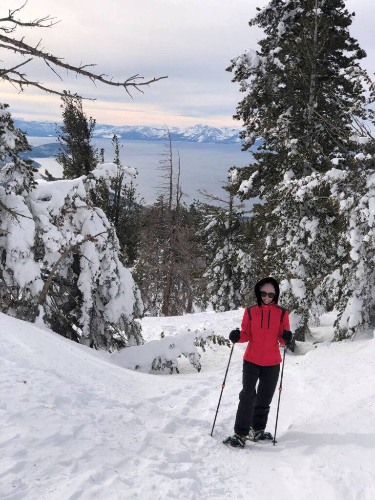 women wearing snowshoes and holding poles in the snow on Chickadee Ridge overlooking Lake Thaoe