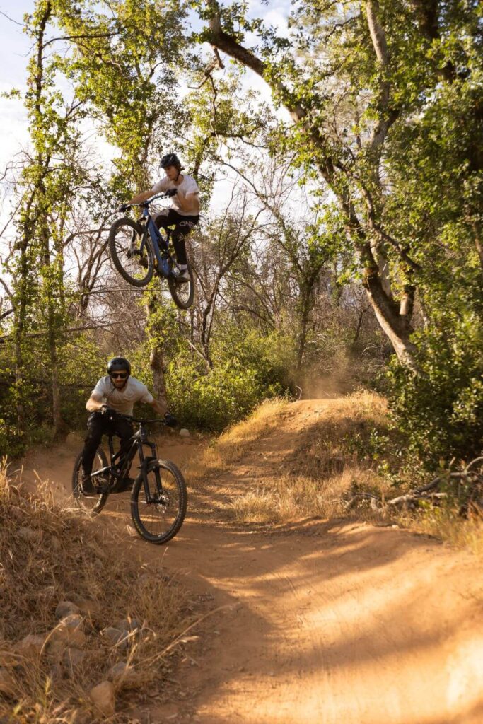 Mountain bike riding in Redding with a two bikers, one on the trail and the other in the air