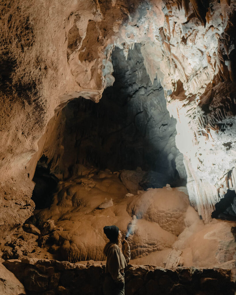 a women shining a flashlight at a stalactites at Lake Shasta Caverns