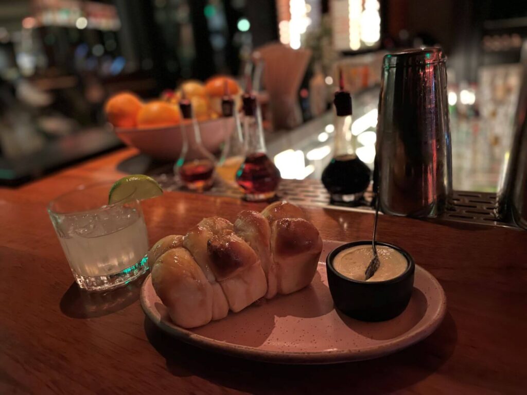 bread, butter, and a cocktail on a bar at VAGA