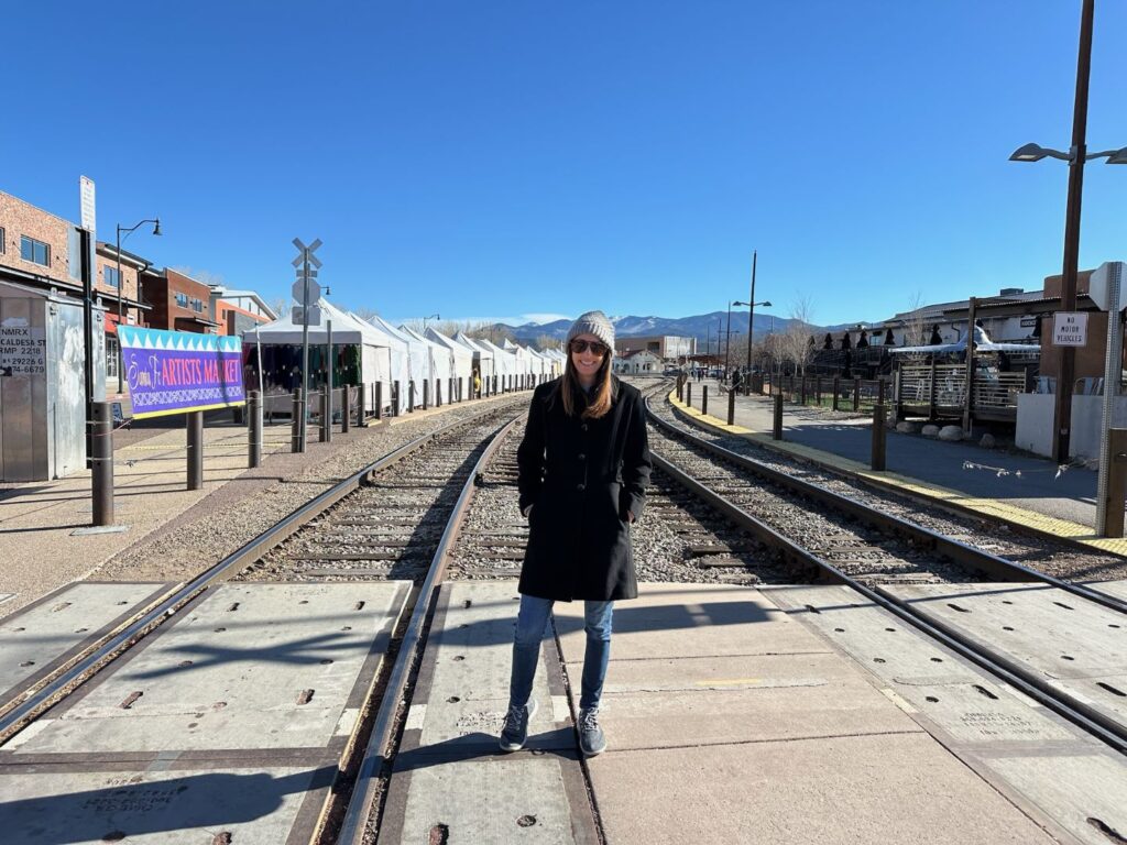 Women standing on the train tracks at the Santa Fe Railyard with vendor tents in the distance