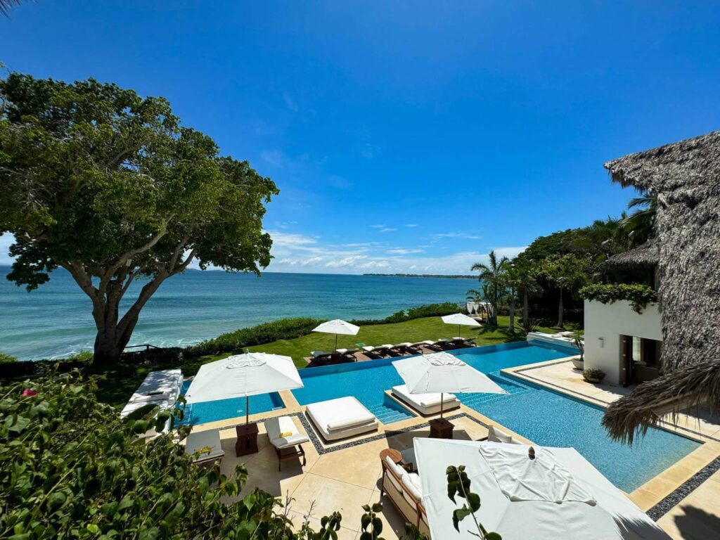 Pool and ocean view with the grass and a luxury villa