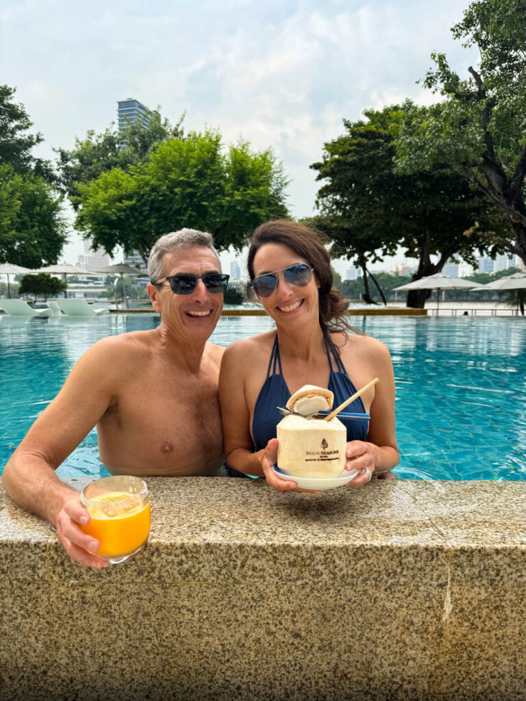 couple at the pool holding drinks Four Seasons Hotel Bangkok at Chao Phraya River