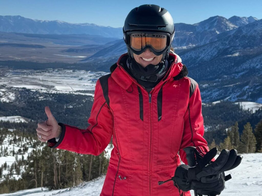 woman at Mammoth Mountain in ski clothes, with a thumbs up