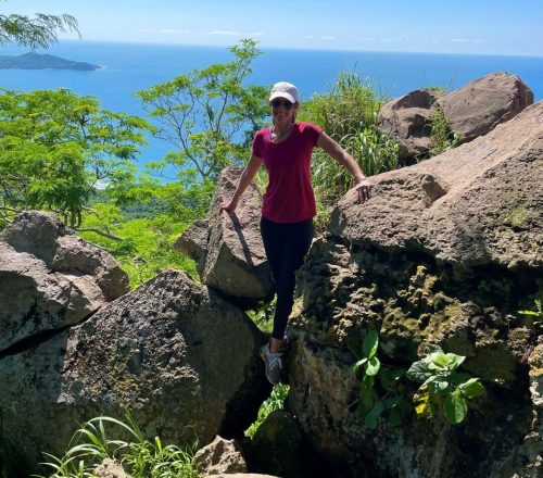 Woman climbing the rocks at the top of Rivera Nayarit Monkey Mountain and view of Banderas Bay