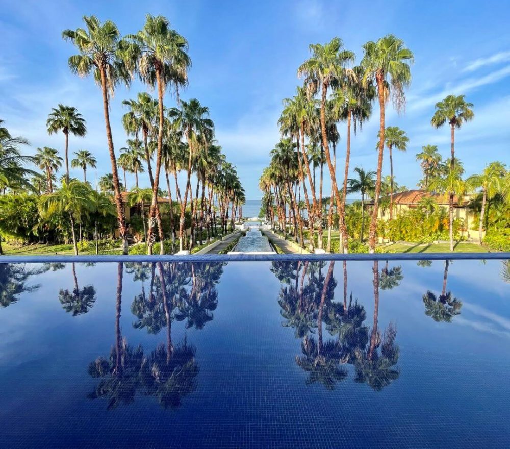 Outdoor check-in area at the St. Regis Punta Mita overlooking a water feature, palm trees and the ocean