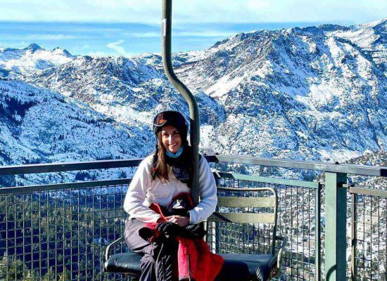 Woman on a chairlift at June Mountain with the Mountains in the background